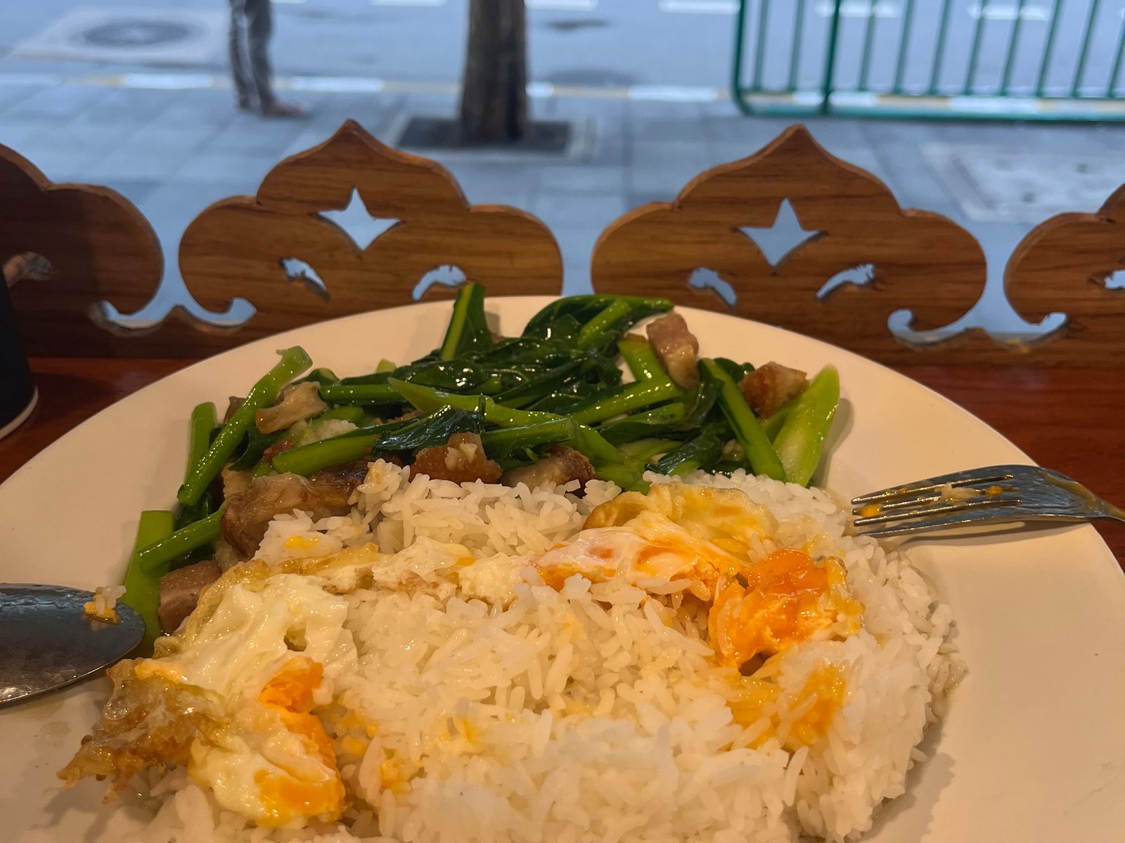 A plate of rice with fried egg and stir-fried greens at a street-side restaurant on Sukhumvit