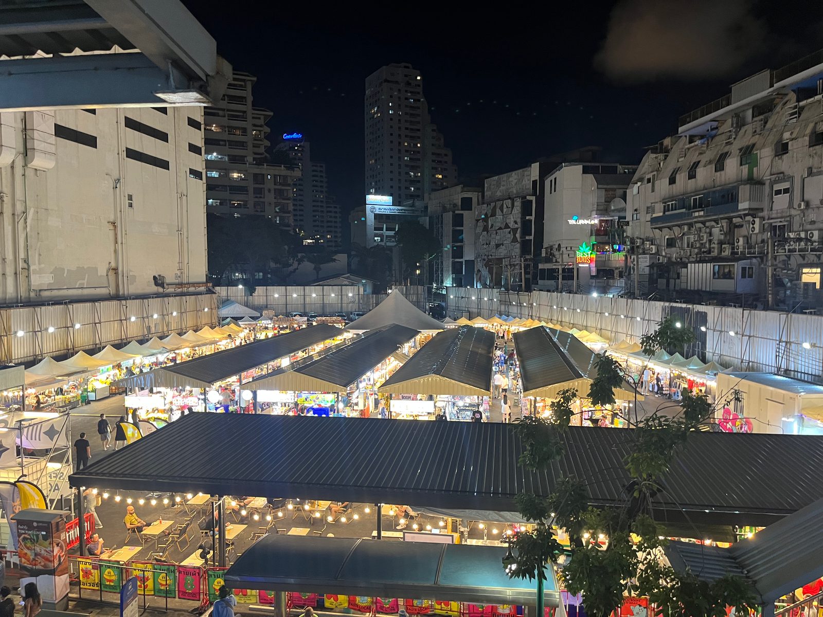 A night market seen from above, with rows of lit stalls between Sukhumvit buildings