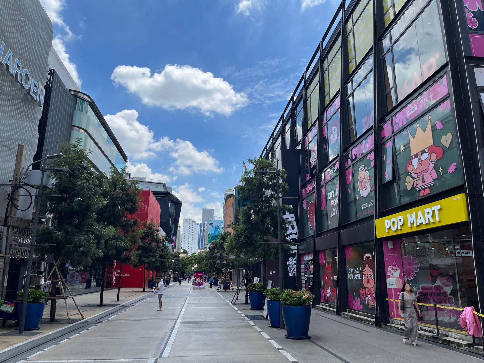 A street in Siam Square lined with shopfronts, a Pop Mart store among them, under a blue sky
