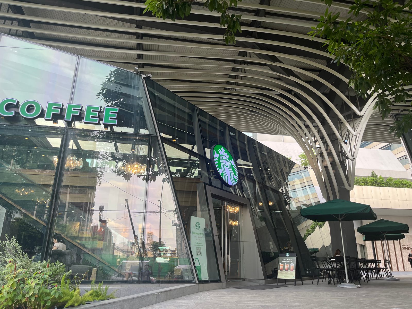A glass-walled Starbucks under a curved steel canopy on Wireless Road, Bangkok