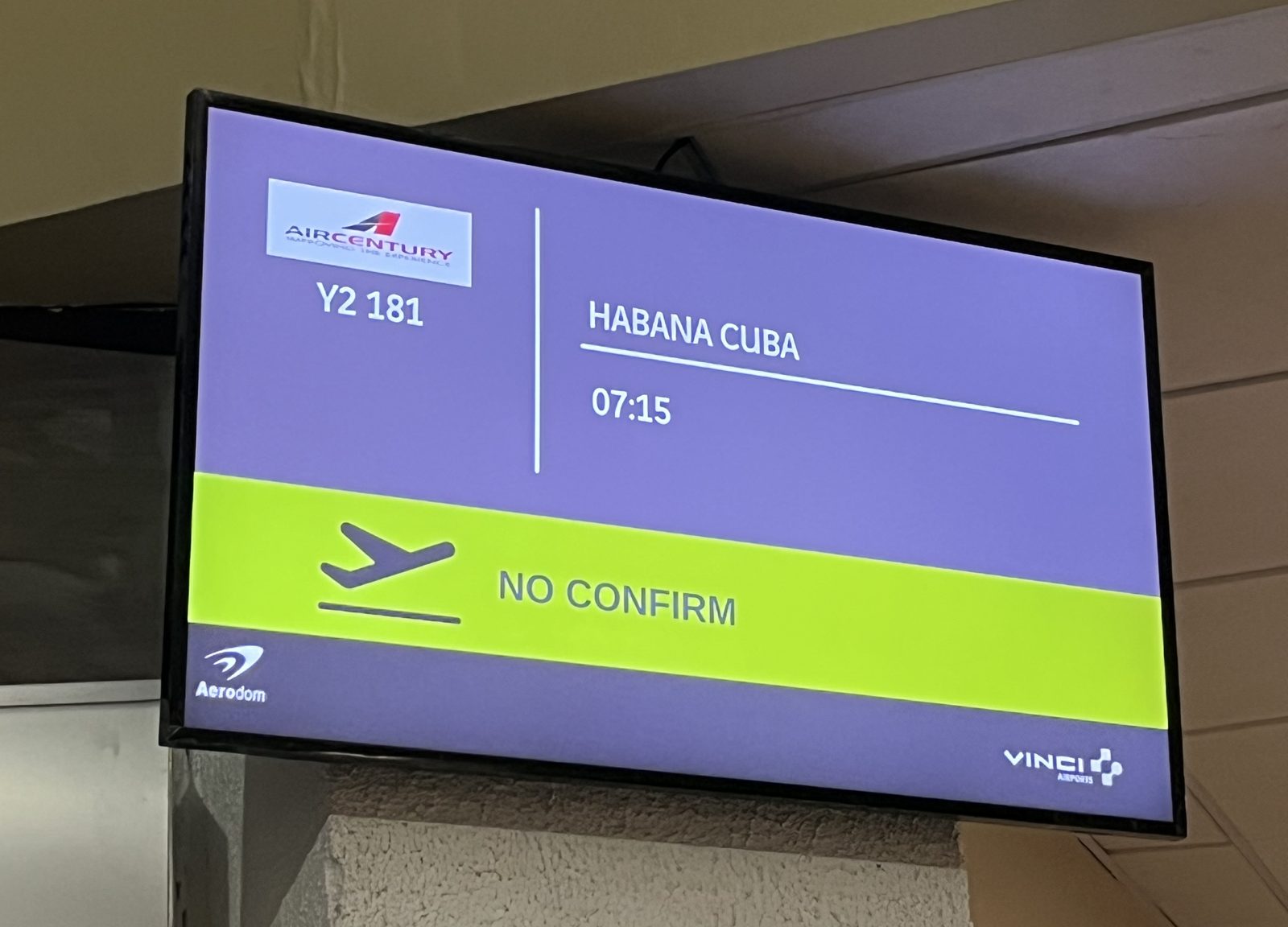 Airport departure screen showing an Air Century flight to Havana marked NO CONFIRM