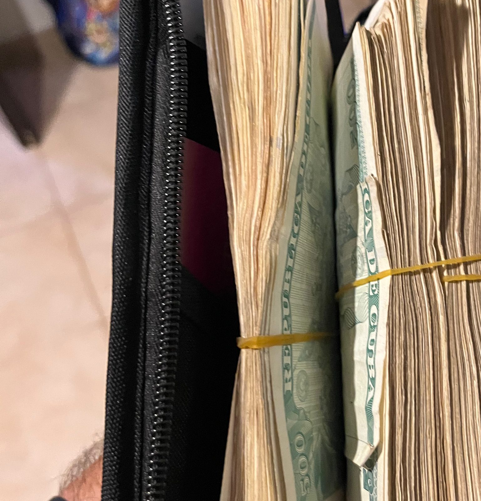 Two thick bundles of banknotes held with rubber bands inside an open travel wallet