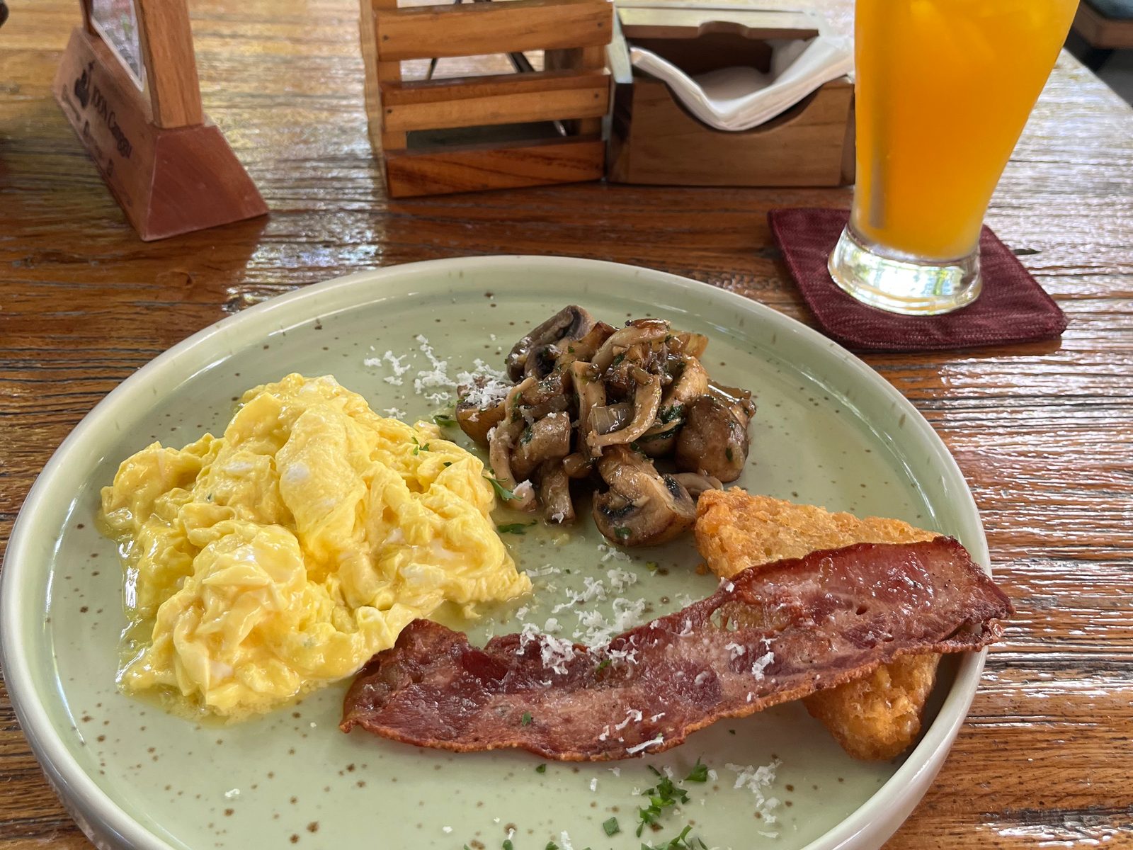 Scrambled eggs, sautéed mushrooms, bacon and a hash brown, with an iced juice behind