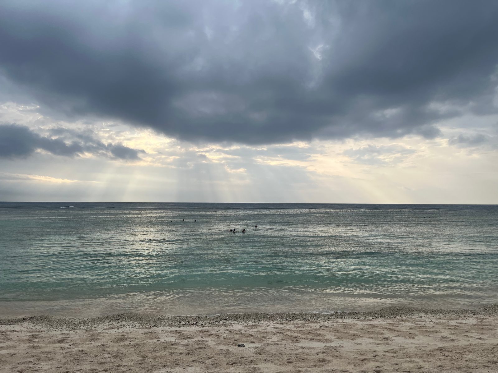 Dark clouds with rays of light over a calm sea off Gili Trawangan