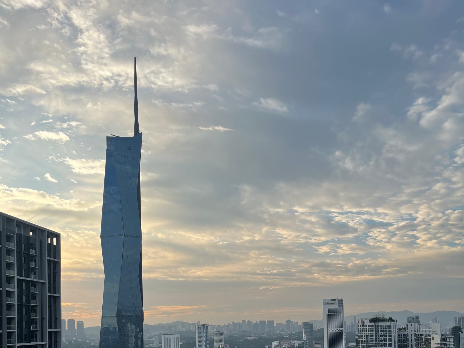 The Merdeka 118 skyscraper against a sunset sky in Kuala Lumpur, with a residential tower on the left