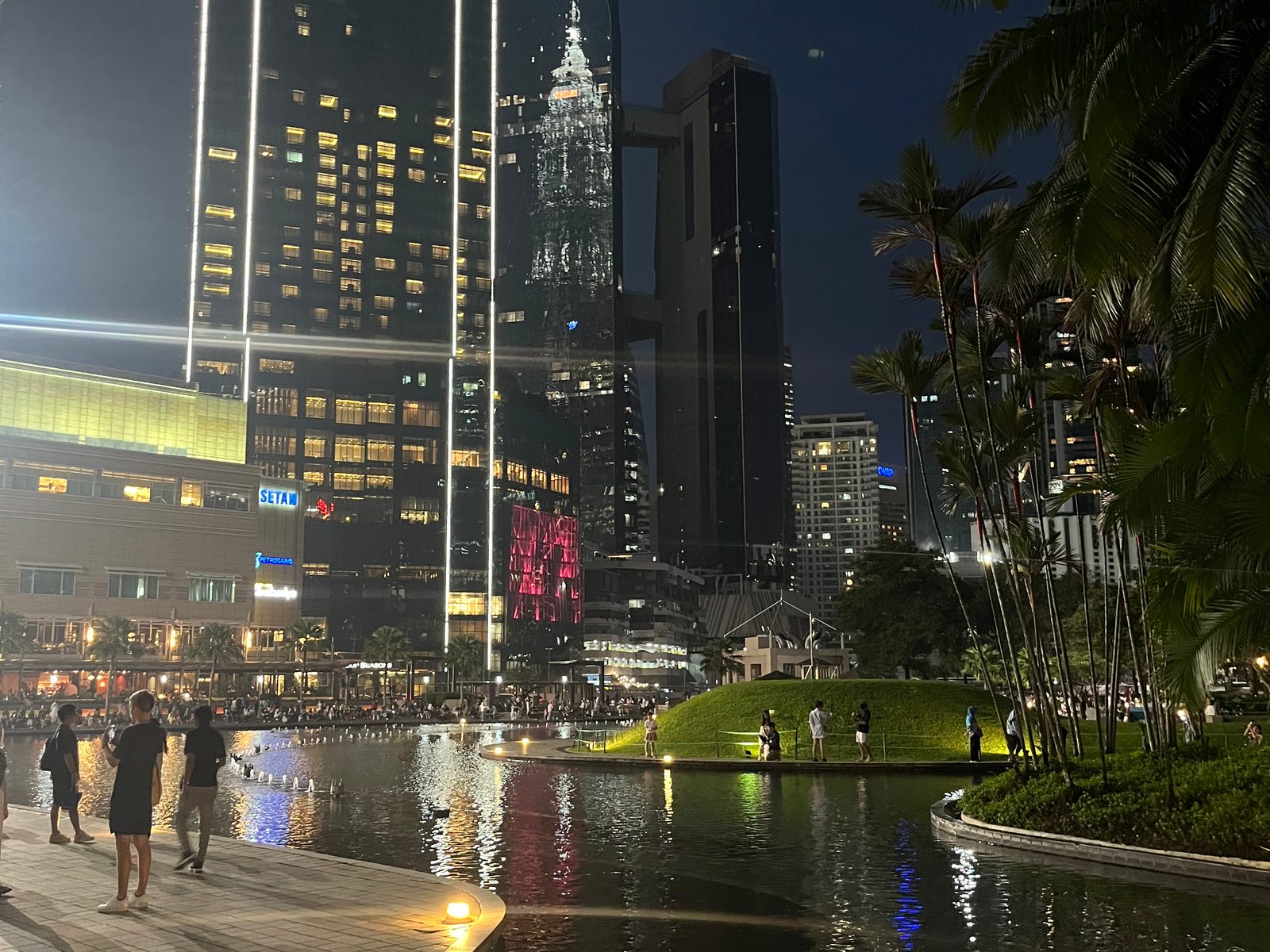 The lakeside path in KLCC Park at night with the lit Petronas Towers behind