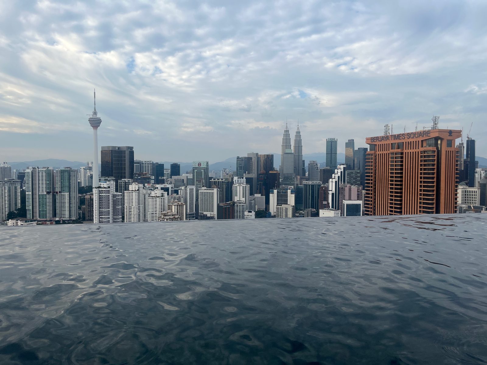 Rooftop infinity pool facing the Kuala Lumpur skyline with KL Tower and the Petronas Towers