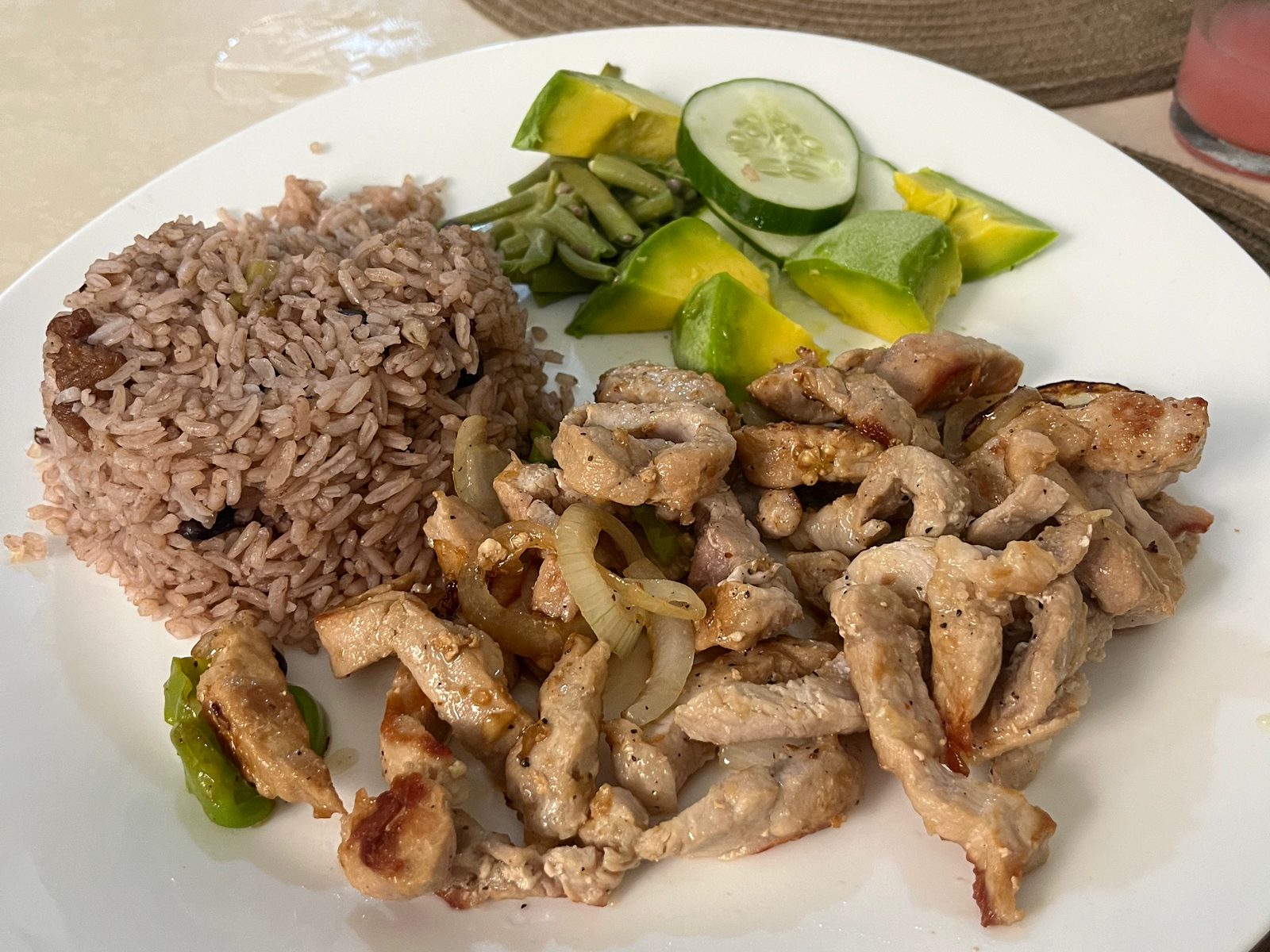 A plate of congrí rice, grilled pork strips, cucumber and avocado