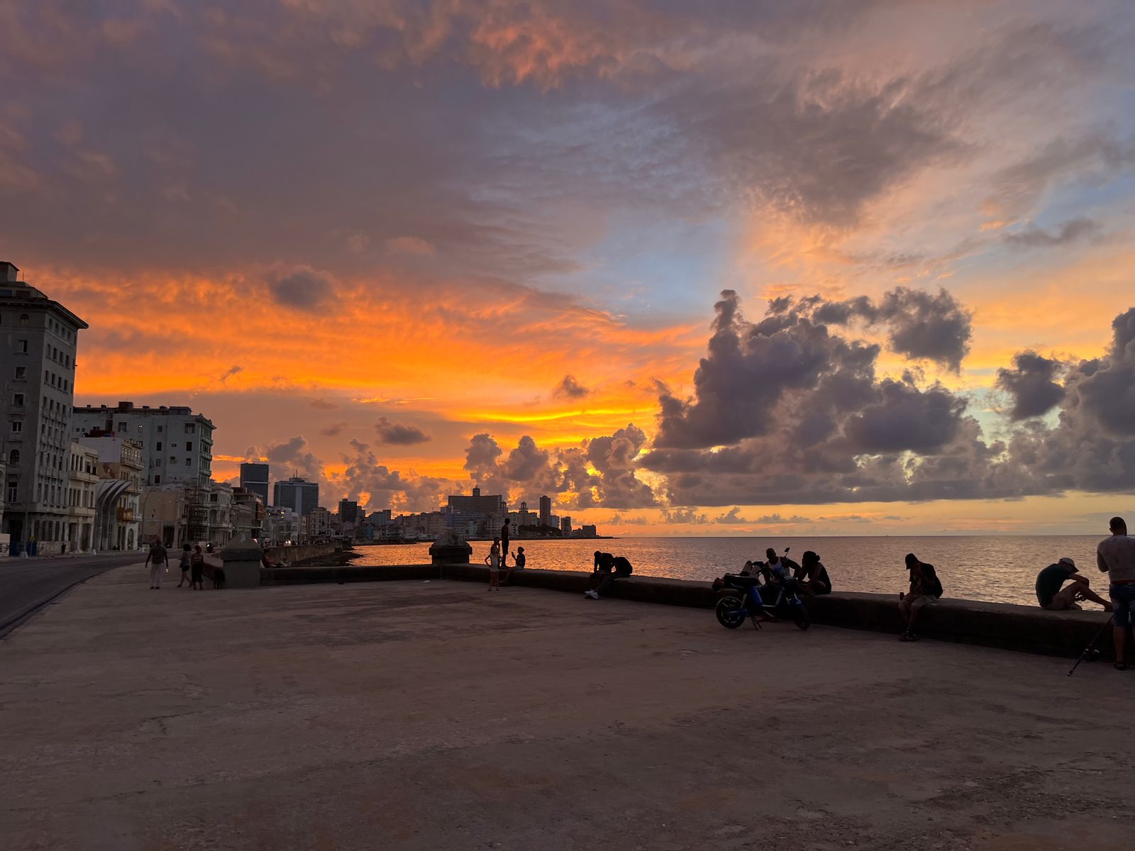 Sunset over the Malecón seawall, with people sitting along it