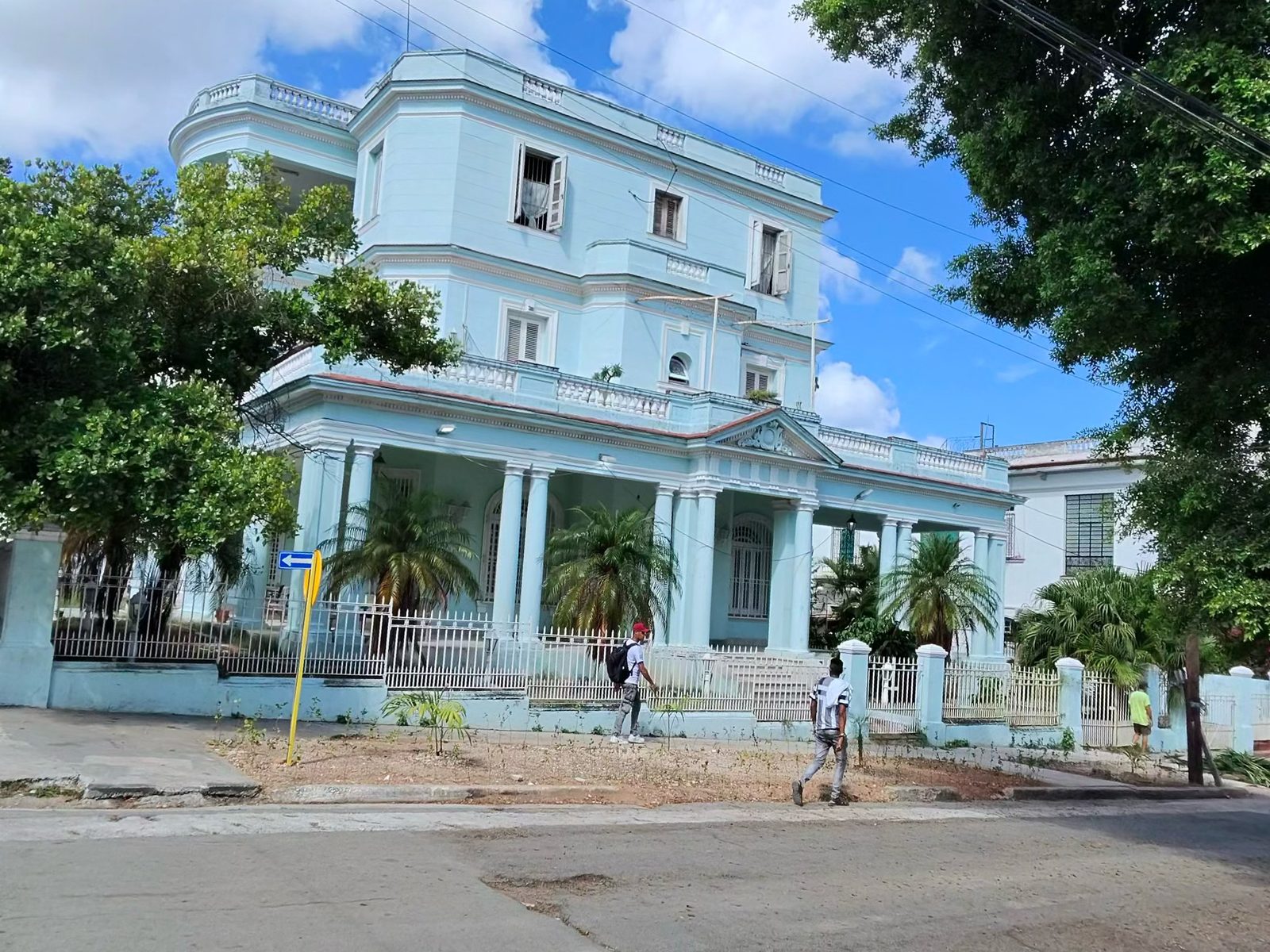 A pale blue mansion among trees on a Vedado corner