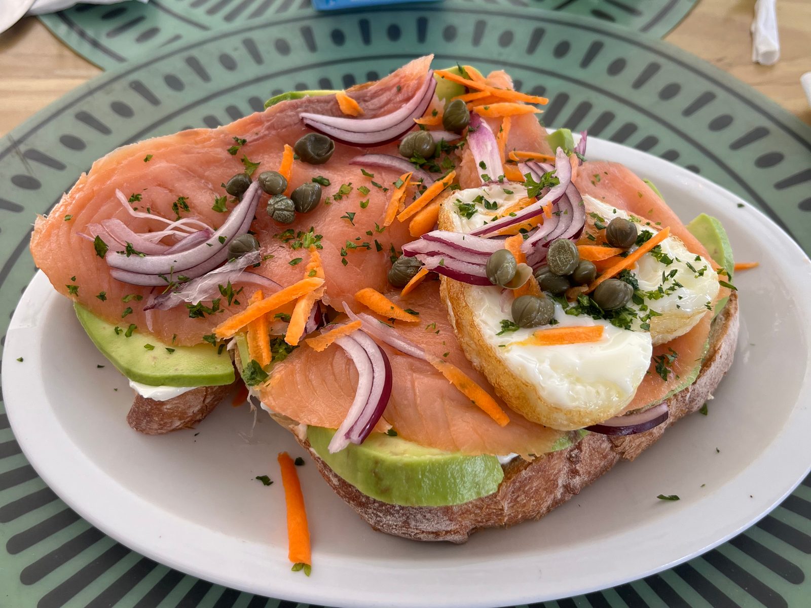 Toast topped with smoked salmon, avocado, egg, capers, red onion and grated carrot