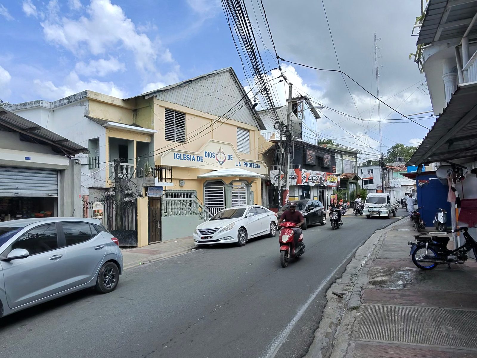 Street in central Las Terrenas with scooters, parked cars and shops