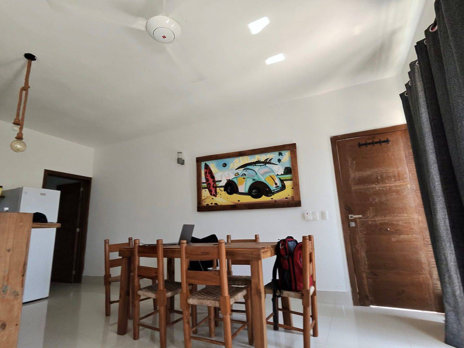 Living room of a furnished apartment with a wooden dining table used as a desk and a ceiling fan