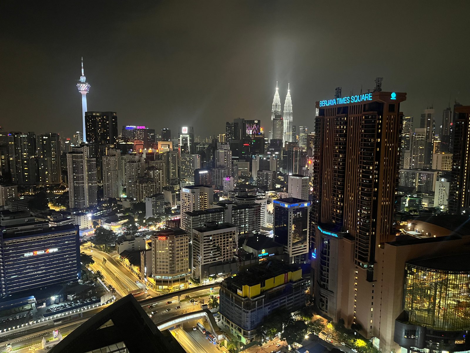 Kuala Lumpur at night from a high floor, with Menara KL, the Petronas Towers and Berjaya Times Square lit up