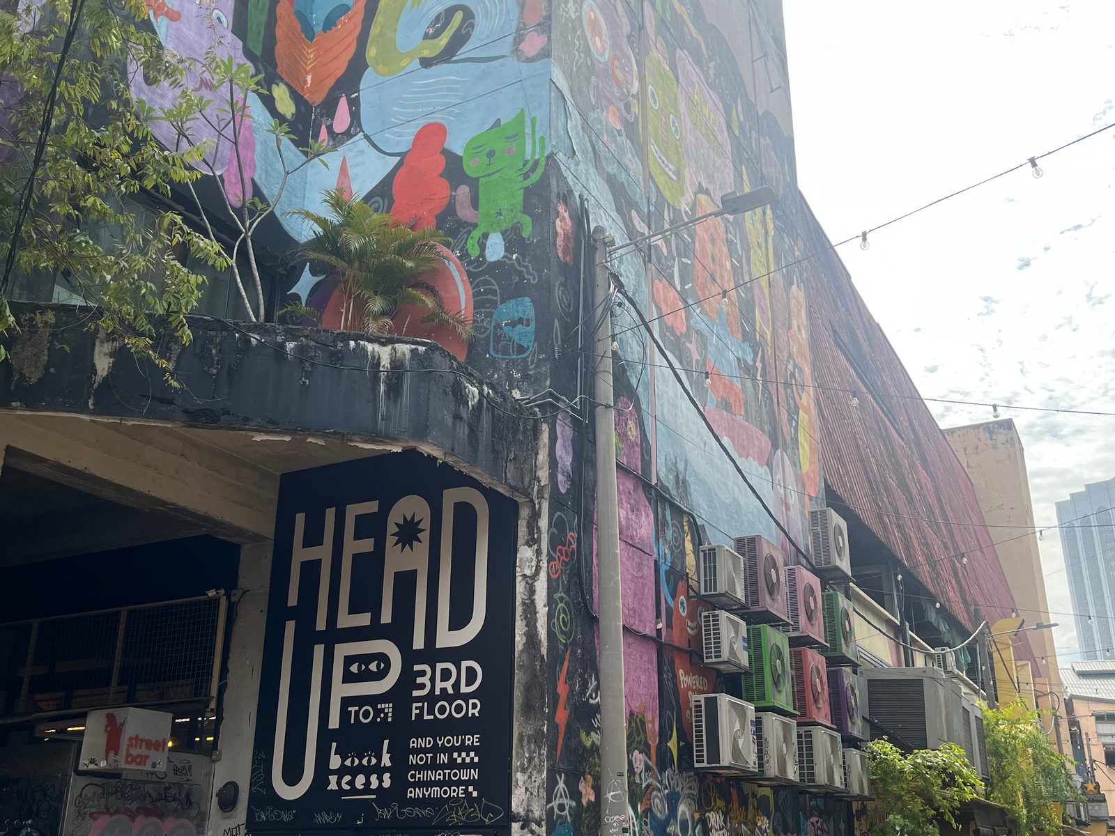 Mural-covered wall of a building in Kuala Lumpur’s Chinatown, with a sign pointing to the bookshop upstairs