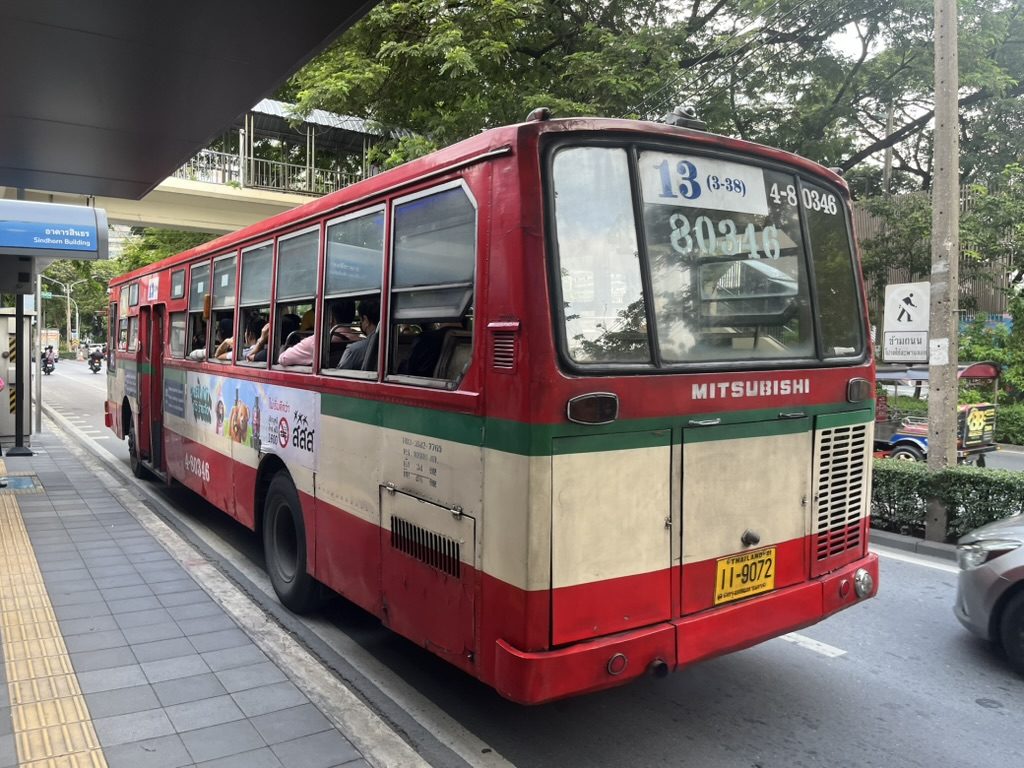 A classic red Bangkok city bus at a stop