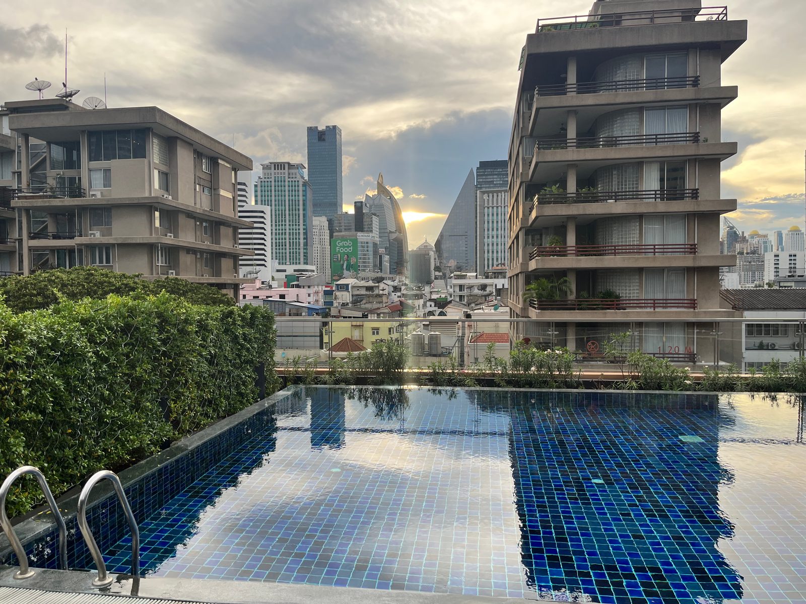 Mid-rise apartment blocks and the Sukhumvit skyline beyond a rooftop pool in Watthana, Bangkok
