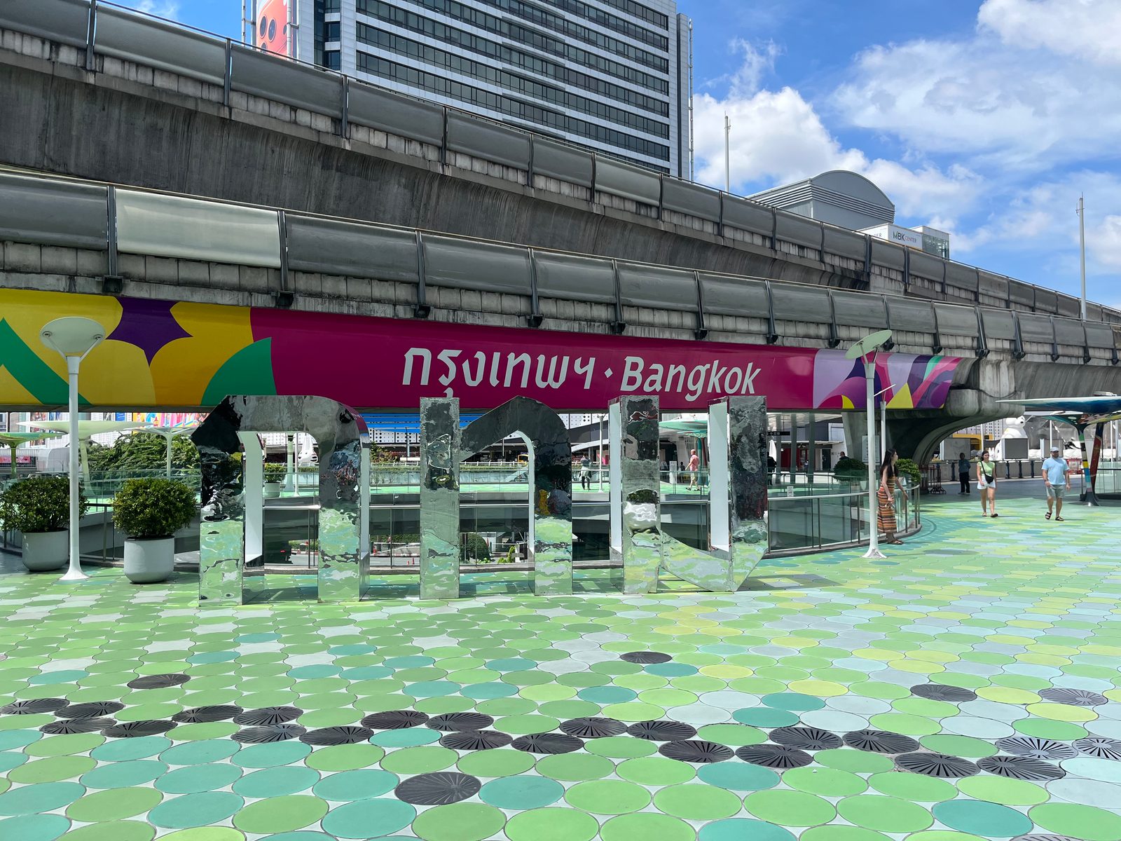 A pink banner reading Bangkok in Thai and English under the BTS skywalk at Siam